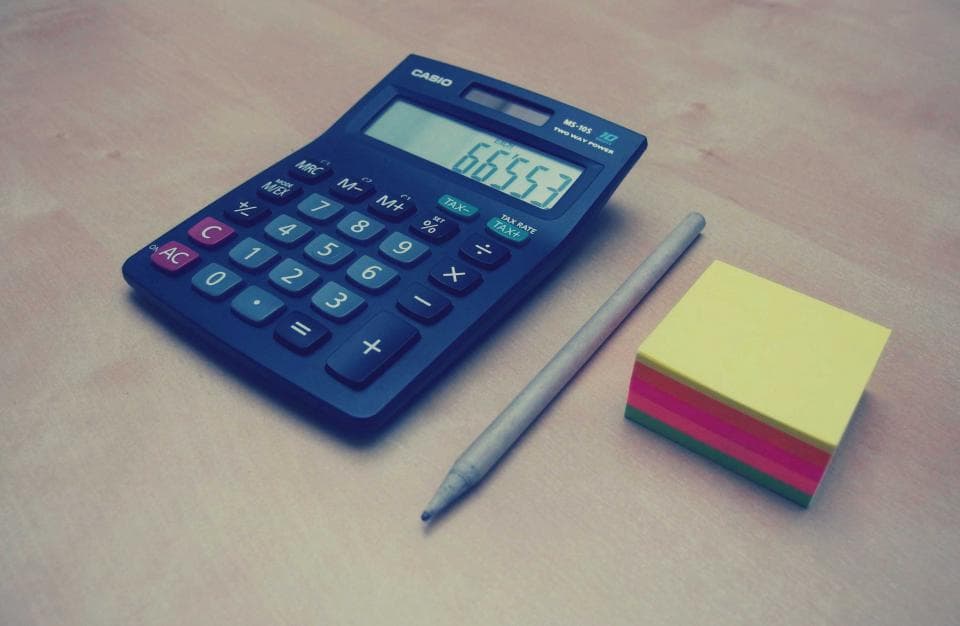 Calculadora azul sobre a mesa ao lado de blocos de anotação